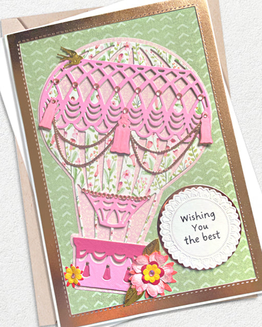 A handmade hot air balloon greeting card with pink and green floral details, a metallic rose gold border, and a white scalloped circle that reads 'Wishing You the best'.