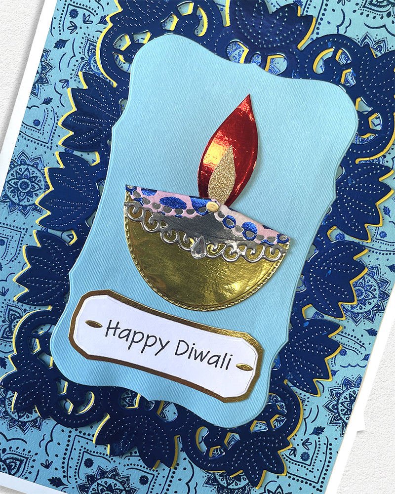 Card with a Diwali design featuring a candle and 'Happy Diwali' text on a blue patterned background.