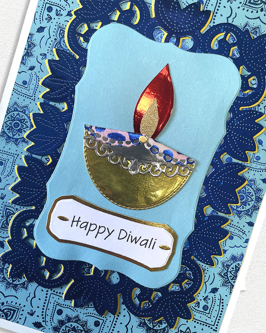 Card with a Diwali design featuring a candle and 'Happy Diwali' text on a blue patterned background.