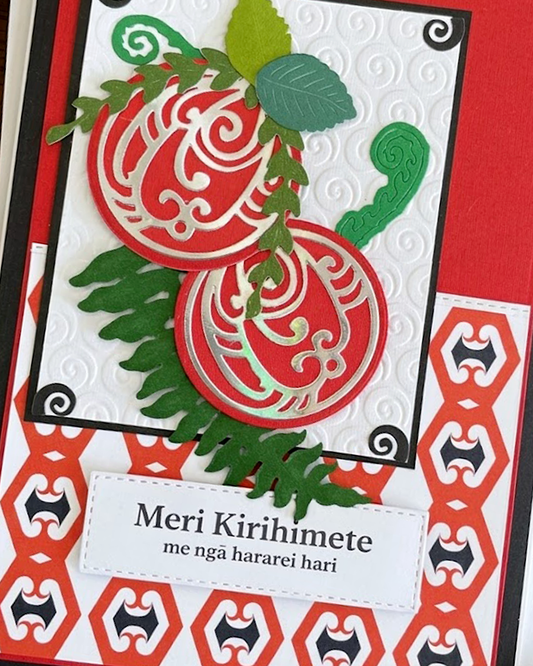 A Maori  Christmas card with intricate Māori patterns, featuring text 'Meri Kirihimete' and 'Merry Christmas and happy holidays' on a red background, with a green leaf and berry design.
