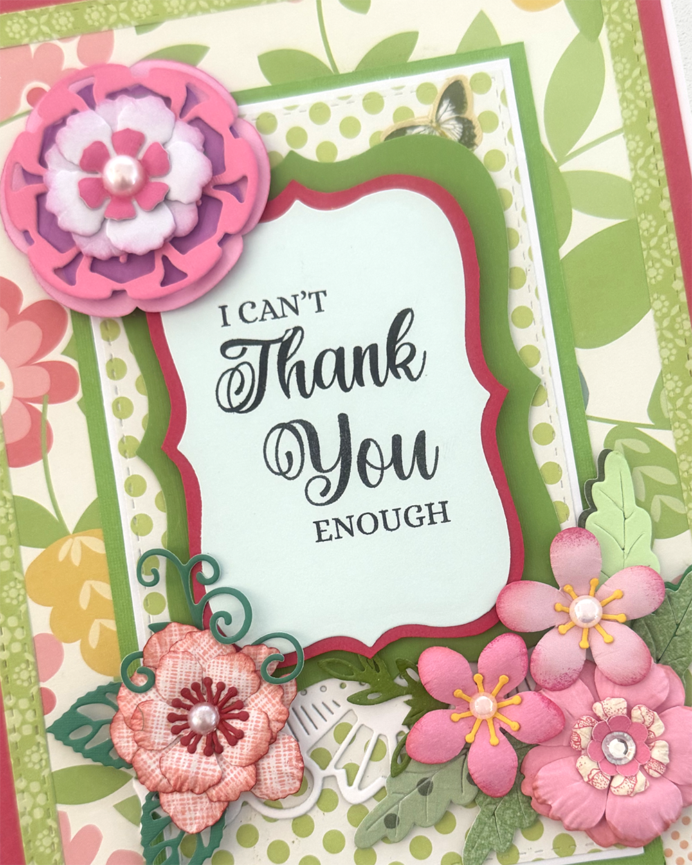 Close-up of hand-layered pink paper rosette and lace-edged red frame on handmade thank you card