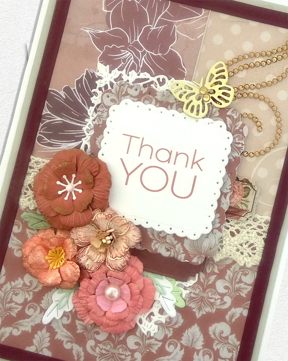 Close-up of gold butterfly and pearl strand above "Thank YOU" sentiment frame