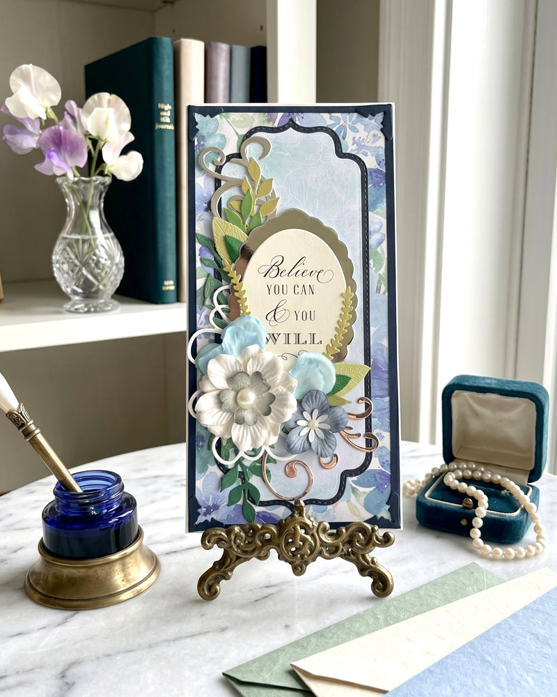 Decorative card with floral design and motivational quote on a marble surface with stationery items.