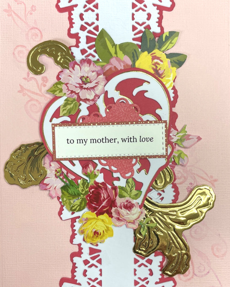 Details of luxury greeting card with a blush pink background layered on a deep rose cardstock mat. A central white lace-style die-cut column runs vertically, flanked by clusters of hand-applied paper flowers in pink, red and yellow roses with green leaves. A decorative die-cut heart frame sits at the centre, holding a sentiment tag reading "to my mother, with love" in elegant italic script. Gold embossed botanical accents — a leaf spray and a butterfly — add warmth and dime

