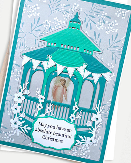 A handmade Christmas greeting card featuring a layered teal and white paper hot air balloon design with a small photo insert, white floral cutouts, and a message card that reads 'May you have an absolute beautiful Christmas'.