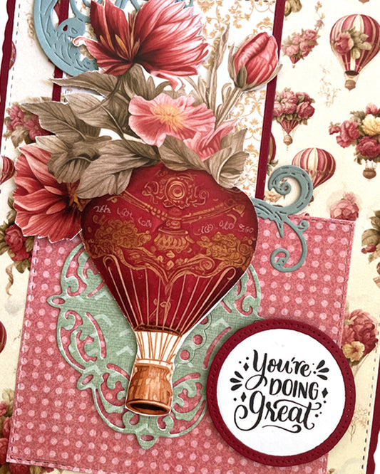 Close-up of a handmade luxury card showing a dimensional vintage red and gold hot air balloon with basket, set against a pink gingham panel, with a circular "You're doing Great" sentiment tag below. Vintage floral patterned background with small balloon illustrations visible. Handmade greeting card made in New Zealand.