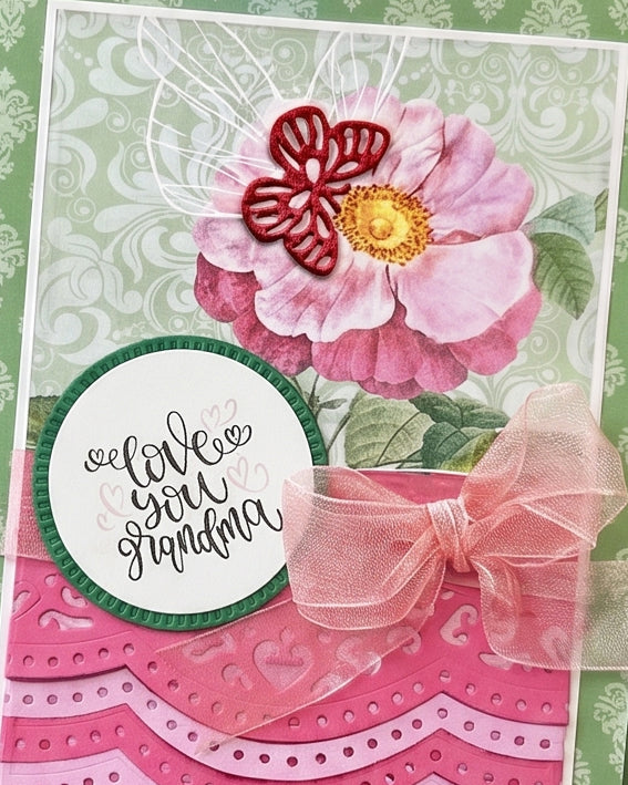 Full front view of a handmade card for grandma featuring sage green damask paper, three layered pink scalloped die-cut border strips, a large pink peony paper flower and a circular "I love you Grandma" sentiment. A heartfelt, elegant grandmother card handmade in New Zealand.