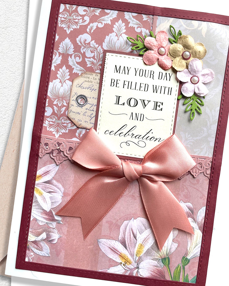 Greeting card with floral design, ribbon, and decorative text on a white background, made in New Zealand by Del Cards NZ.