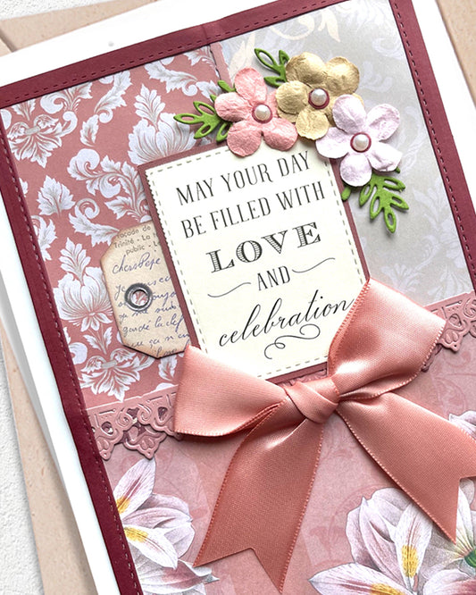 Greeting card with floral design, pink ribbon, and decorative text on a floral background.