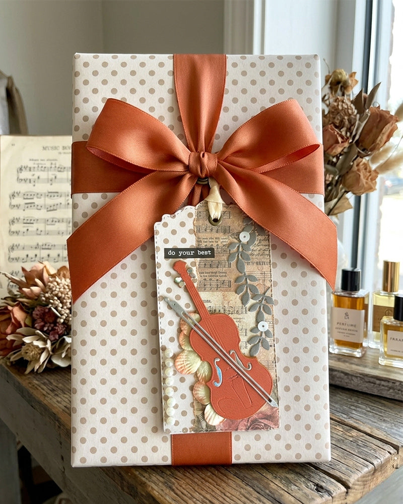 Luxury handmade music gift tag styled on a wrapped gift with terracotta satin bow and dried botanicals — Del Cards NZ handmade gift tags are perfect for musicians, recitals and music exam celebrations
