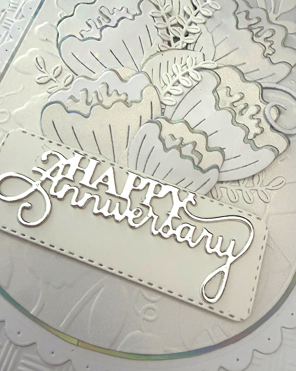 Happy Anniversary sentiment in silver foil script on stitched-edge tag, close-up detail
