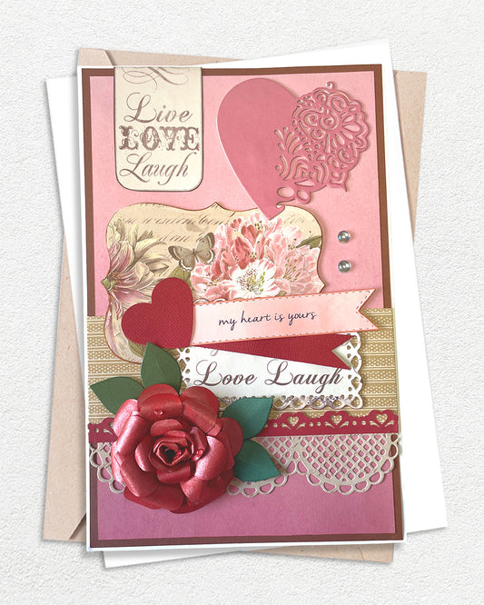 Luxury handmade love card featuring a large dimensional deep red rose, lace doily, and layered pink and cream panels with vintage floral imagery, red heart die-cut, and sentiment banners reading "Live Love Laugh," "my heart is yours," and "Love Laugh"