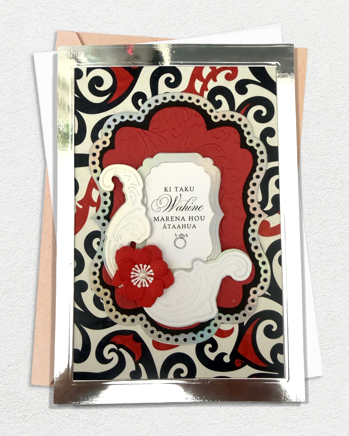 Luxury handmade Te Reo Māori wedding card with floral design and traditional red and black patterned background, made in Auckland New Zealand