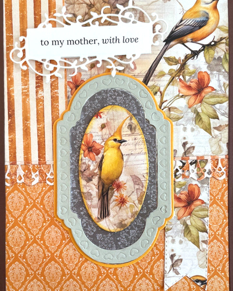 Front view of a handmade luxury greeting card for mothers, featuring warm amber damask paper, a raised oval frame with a golden songbird, autumn berry and leaf botanicals, ivory pinstripe panel, and an elegant "to my mother, with love" sentiment tag. Handmade in New Zealand by Del.

